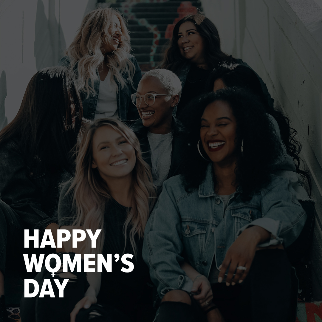 Group of women's smiling on steps with the text "Happy Women's Day"
